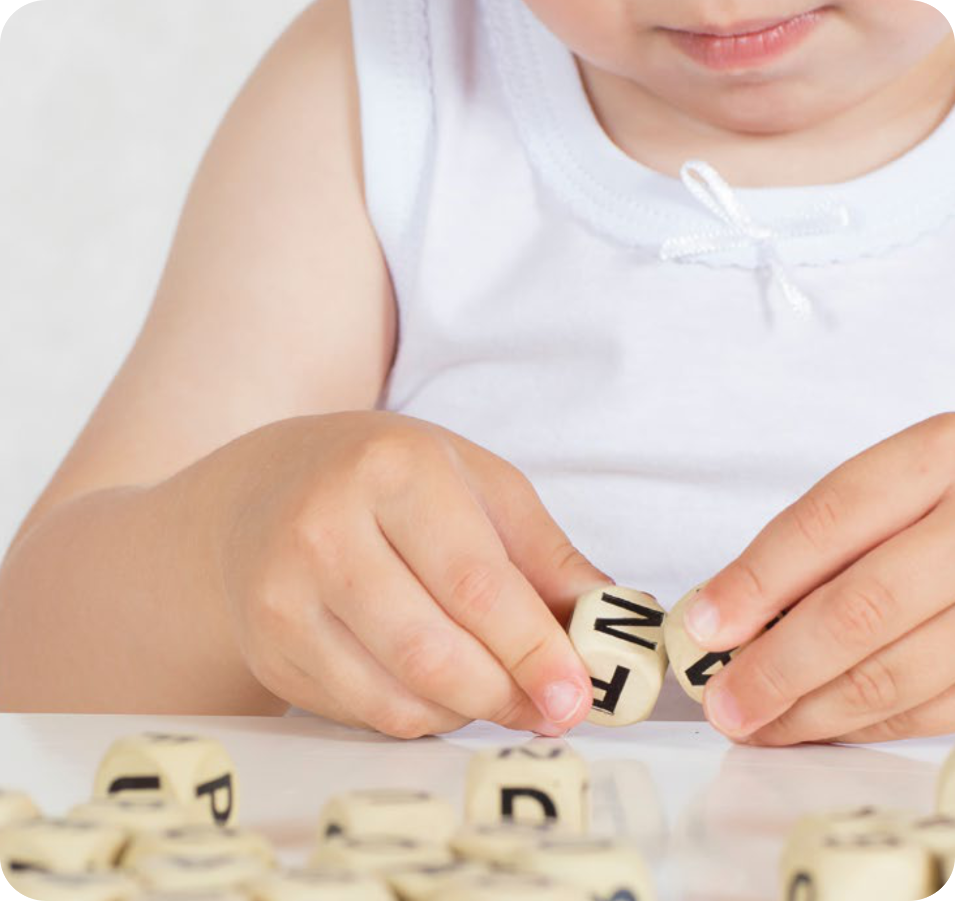 Niña de 1 año jugando con dados con letras de madera